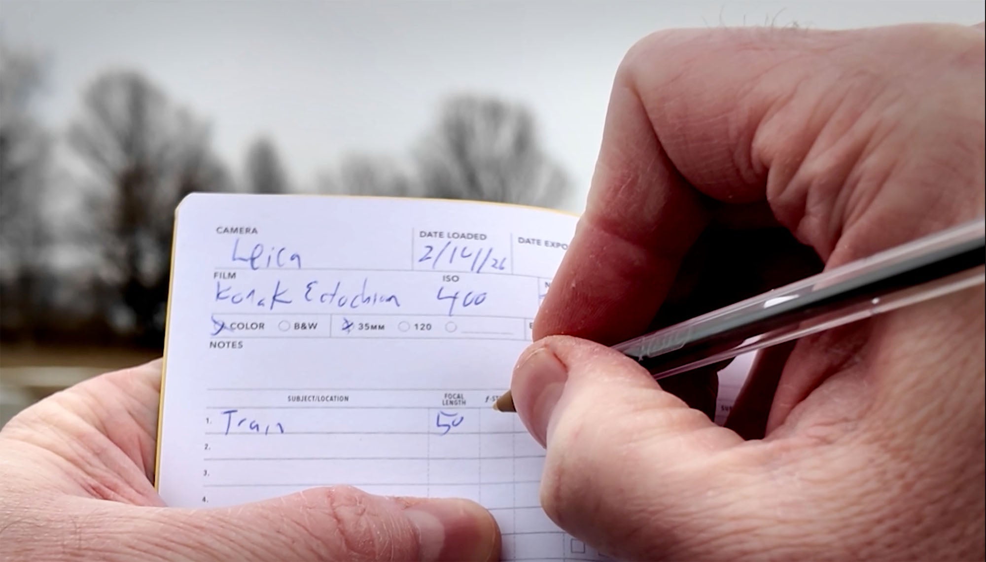 Writing the camera and film info down in the WRKBKS film log