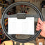 Steering wheel with a clip holding a Cart Rider's Golf Log in a workshop setting