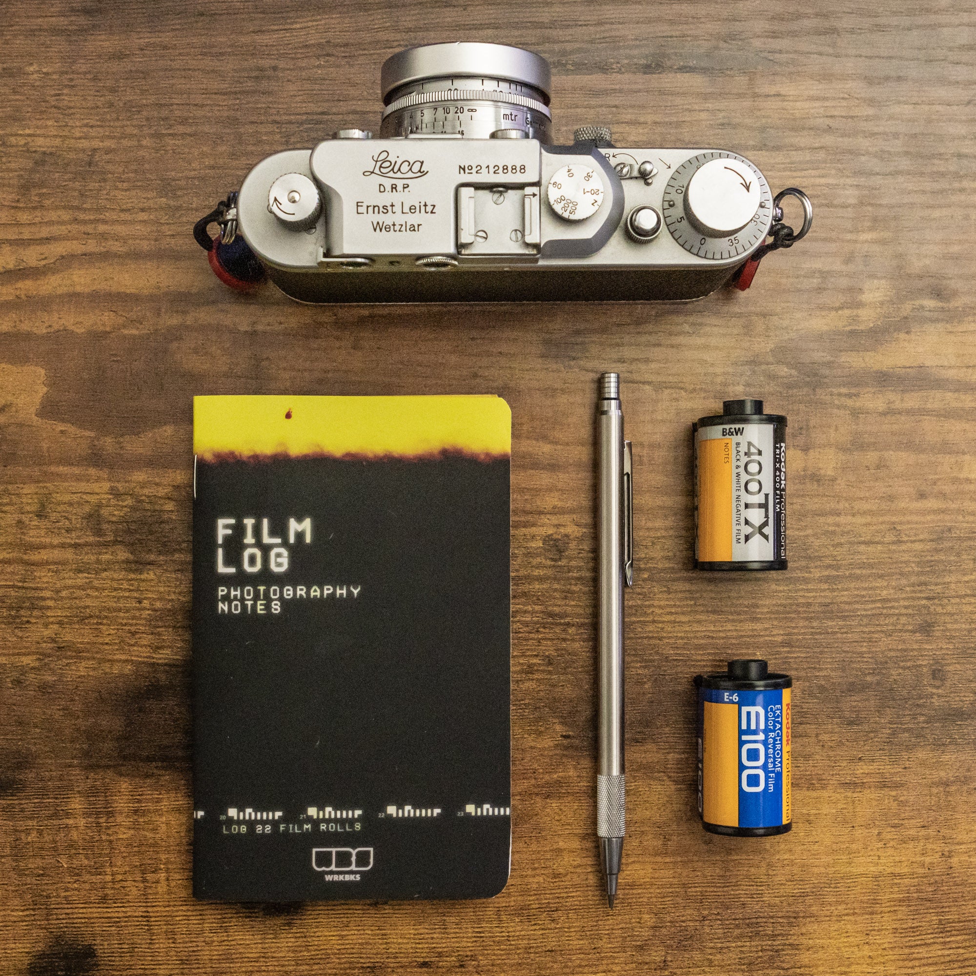 A Leica III film camera with 2 rolls of film, a mechanical pencil and the WRKBKS Film Photography Log
