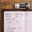 A roll of 120 film with a filled out page of the film photography log.