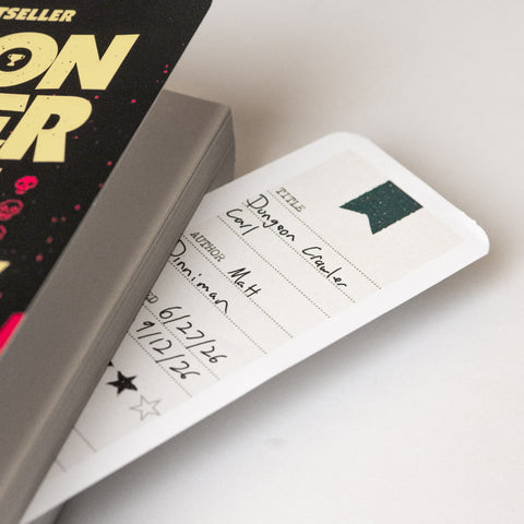 Reading log bookmarks tucked in a paperback book
