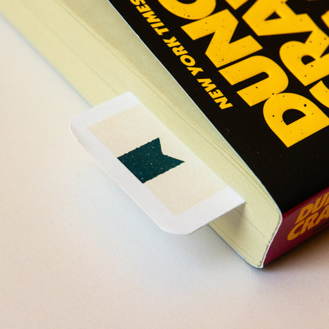 Reading log bookmarks tucked in a paperback book