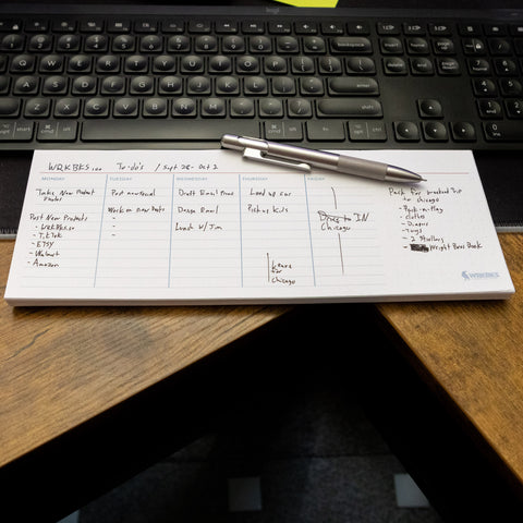 Filled out weekly planner notepad on a desk in front of a keyboard